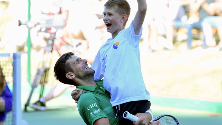 Djokovic celebrates with a young supporter during his friendly match against Dodig.