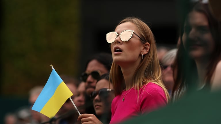 A spectator holding a Ukraine flag watched Marta Kostyuk play at the All England Club.