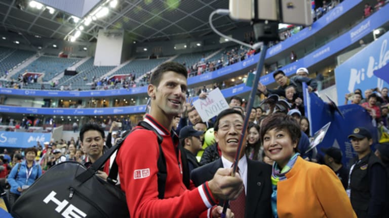 Novak Djokovic of Serbia, center, takes a selfie with officials after winning his men