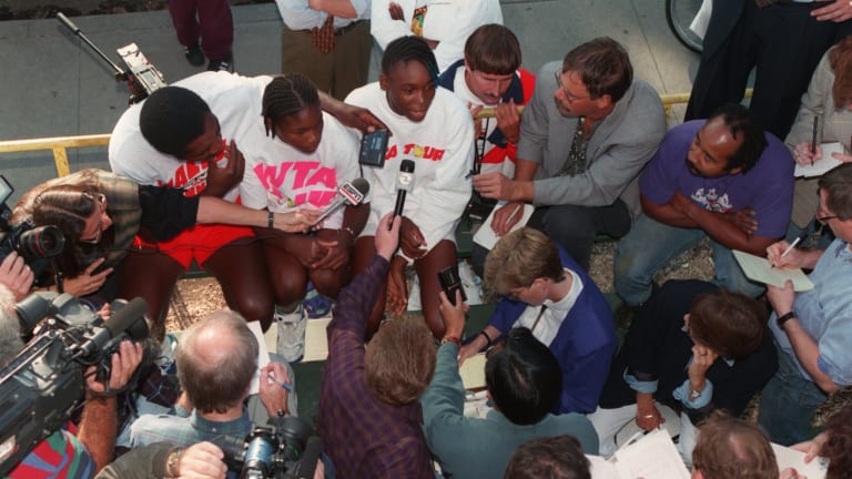 Venus speaks with press at the El Mont Tennis Center, accompanied by a 13-year-old Serena and their father Richard.