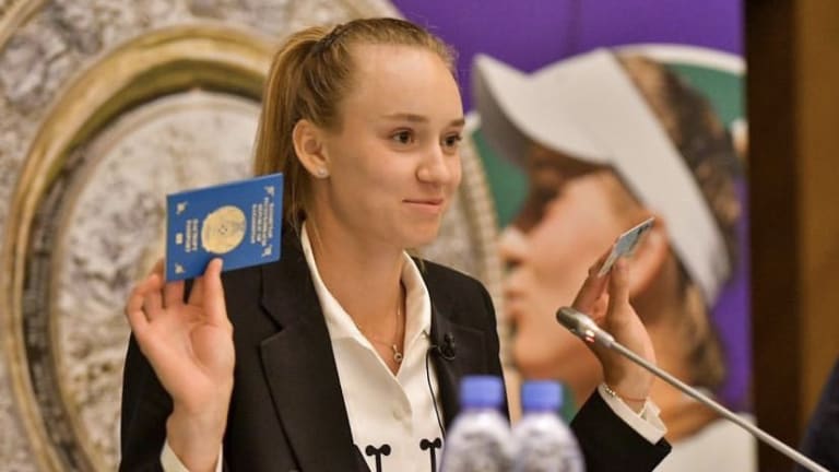 Rybakina shows off her Kazakhstan passport and national ID card during a press conference.