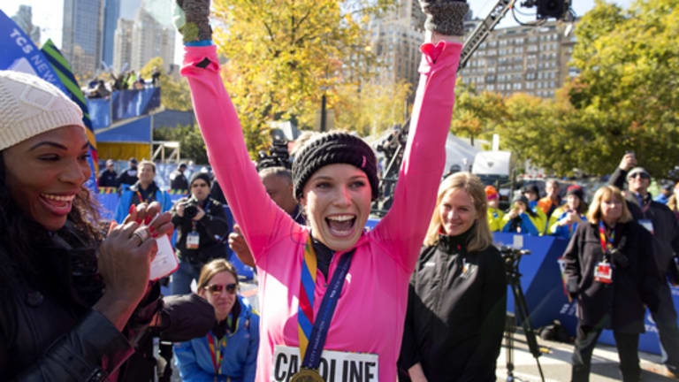 Tennis player Caroline Wozniacki raises her hands after getting a medal for completing the New York City Marathon in New York Sunday, Nov. 2, 2014. Left is tennis player Serena Williams. (AP Photo/Craig Ruttle)
