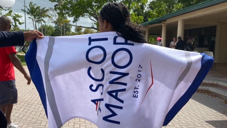 Junior tennis player holds up Ascot Manor towel.